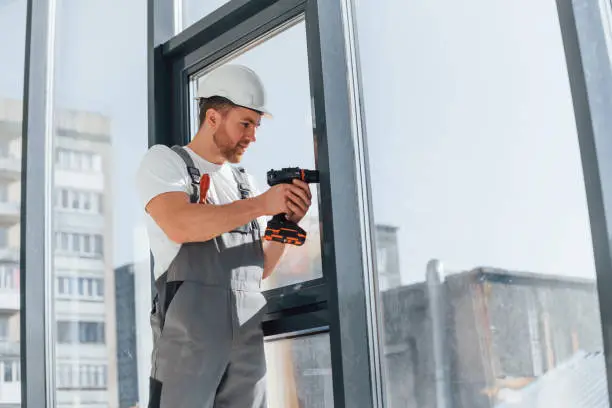 Focused on the work. Repairman is indoors in the modern room.